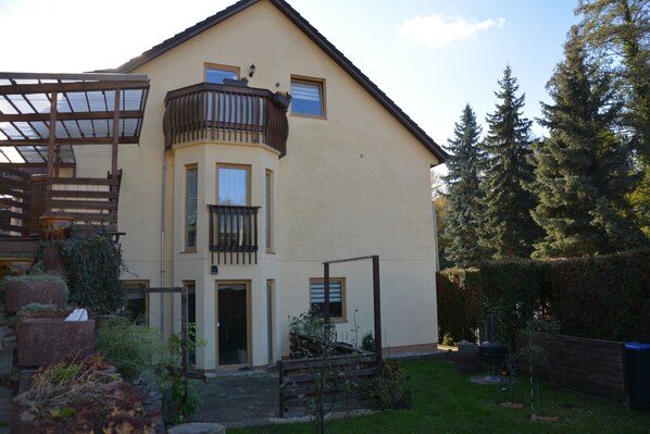 A two-story house with a balcony, a covered porch, and a well-maintained garden. - Living in the countryside (Dresden)