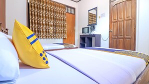 Een hotelkamer met een bed, een televisie op een bureau en een houten deur.