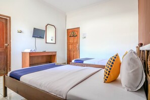 A hotel room with two beds, a wooden desk, a television, and a door with a decorative glass panel. - OYO 1927 Hotel Candra Adigraha (Denpasar)