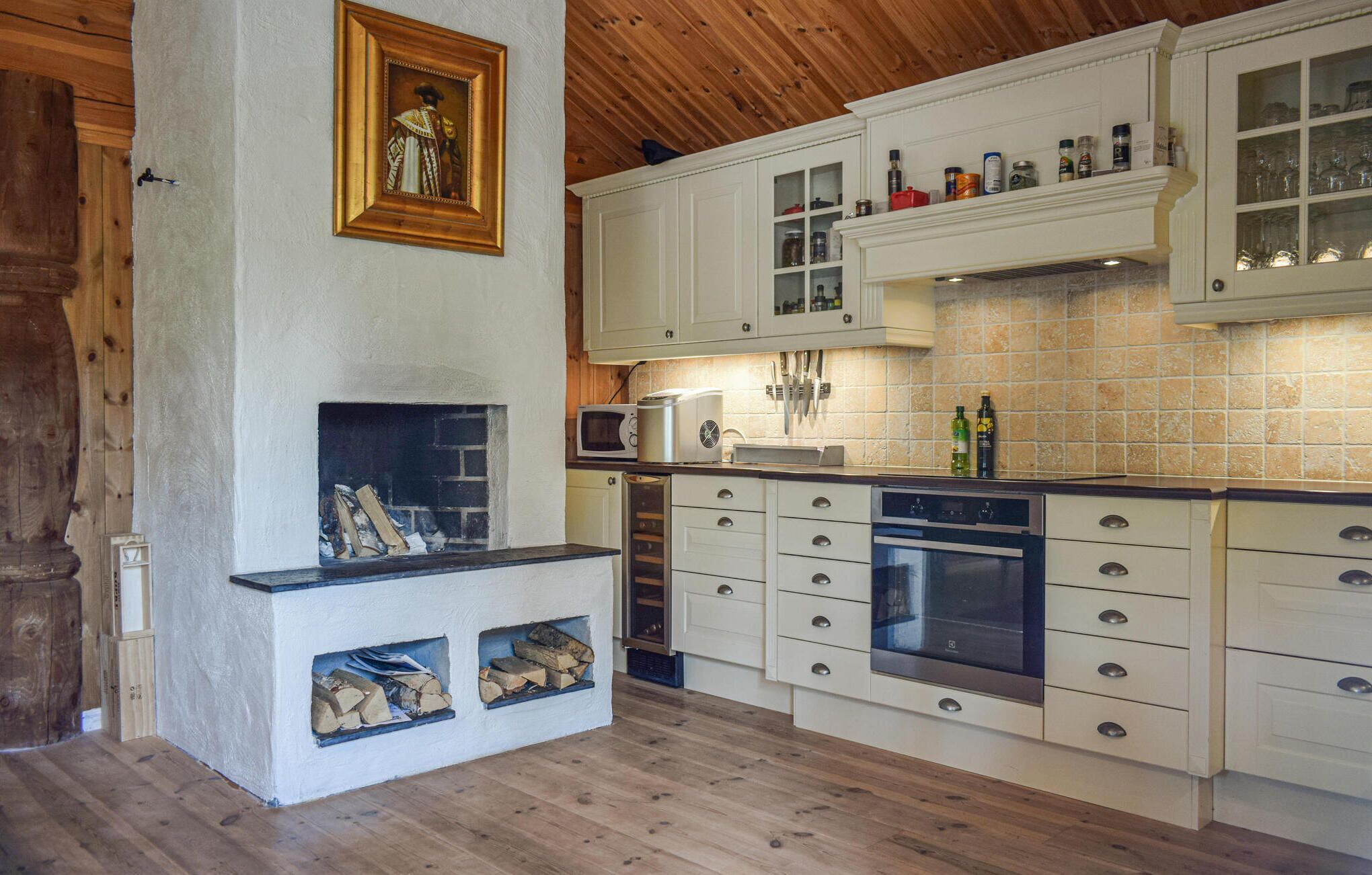 A kitchen with white cabinets, a built-in microwave, a stove, and a fireplace with wood logs.
