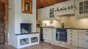 A kitchen with white cabinets, a built-in microwave, a stove, and a fireplace with wood logs. - Cozy home in Hemsedal with kitchen (Hemsedal)