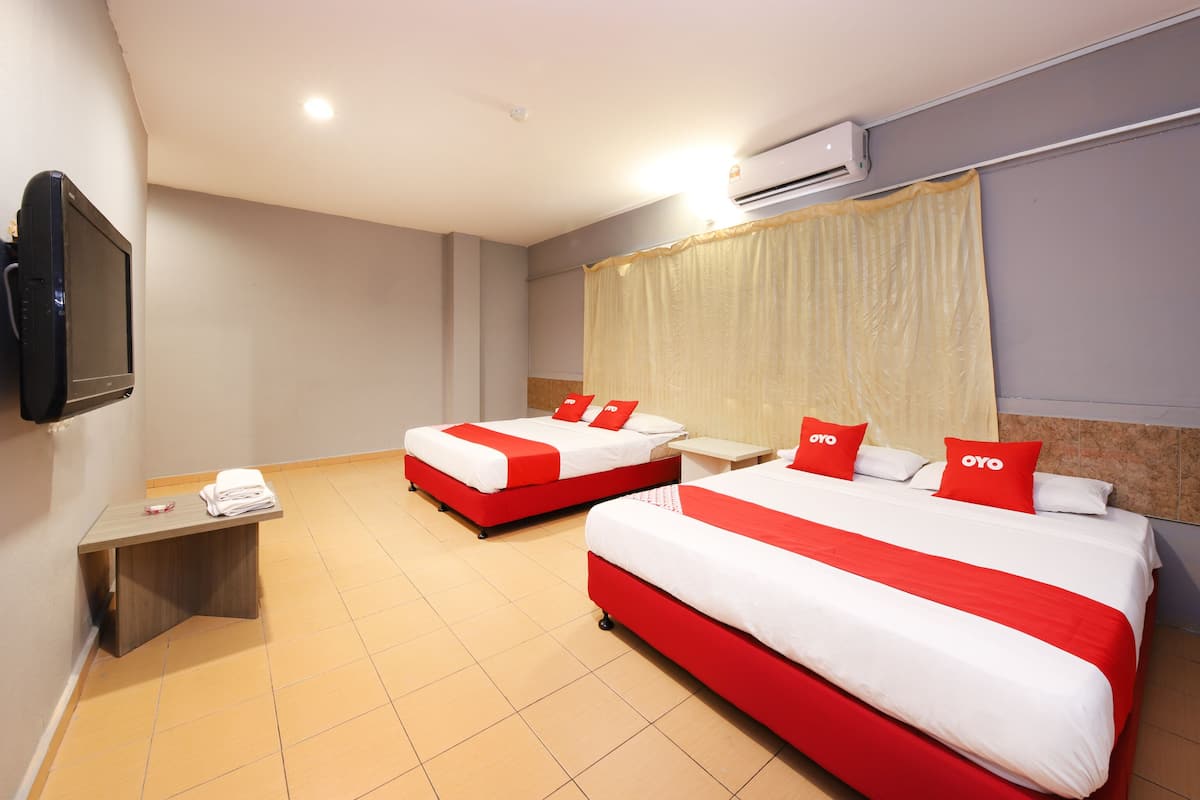 A hotel room with two beds, a TV, an air conditioner, and a small desk.