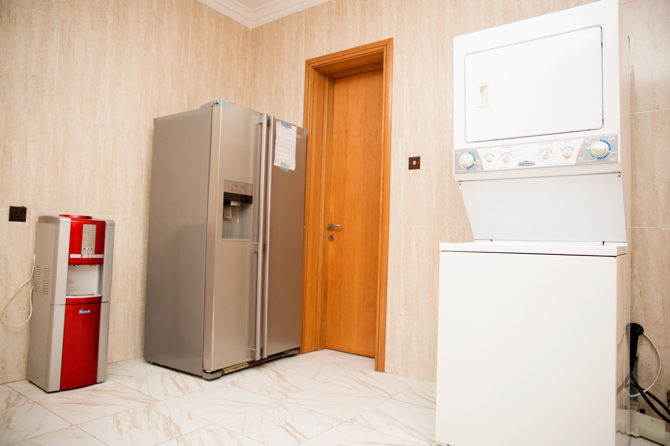 A compact kitchen with a refrigerator, a water dispenser, and a washing machine.