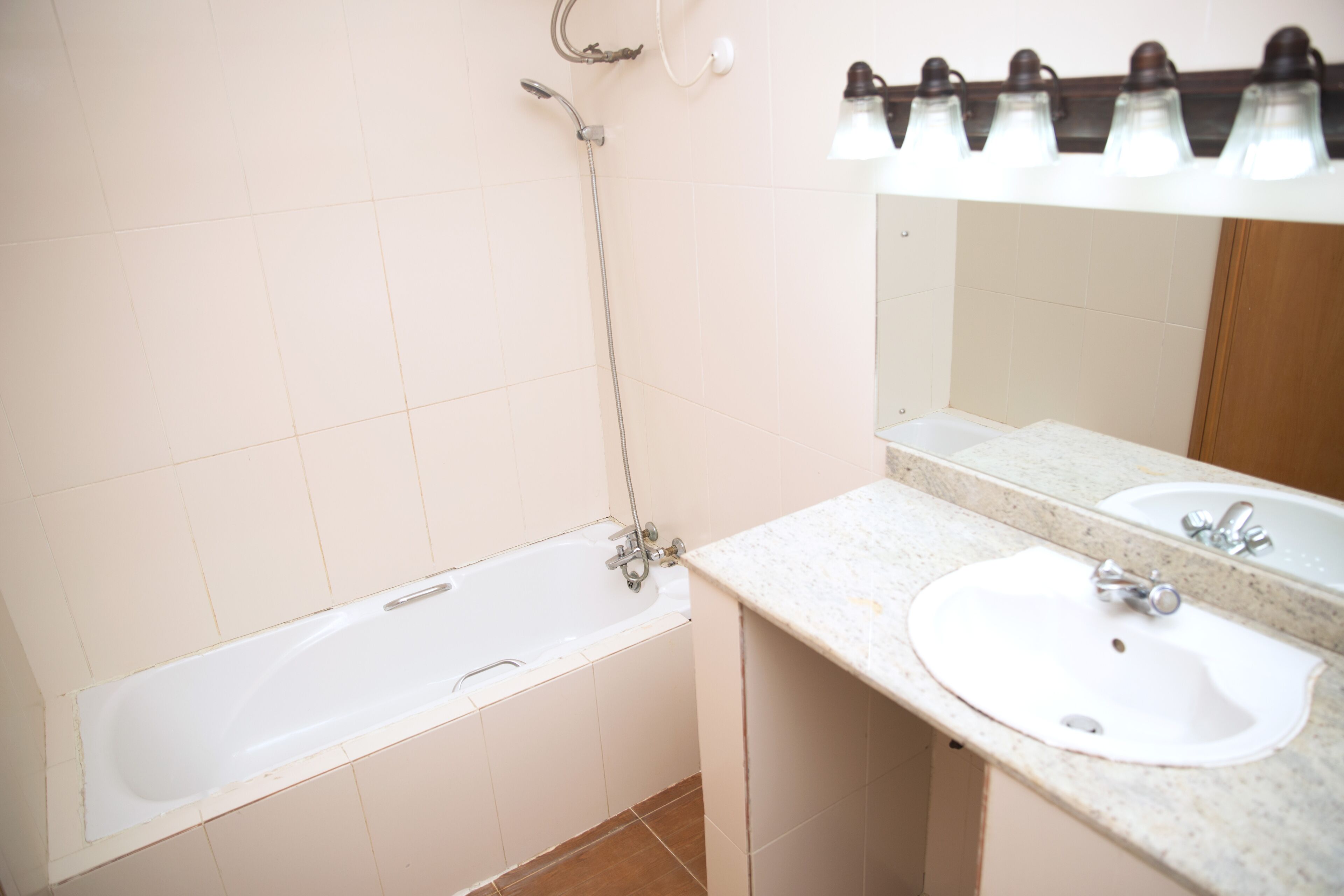 Une salle de bain avec une baignoire, deux lavabos, un miroir et une pomme de douche.