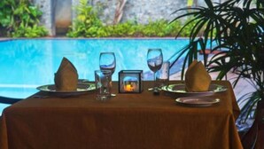 A table set for two with a view of a pool and greenery in the background. - Hotel Sunflower (Kataragama)