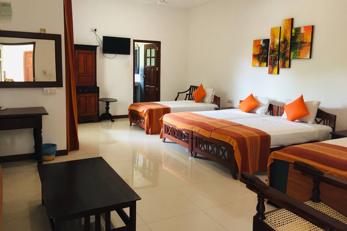 A hotel room with two beds, a desk, a chair, a TV, and artwork on the wall.