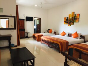 A hotel room with two beds, a desk, a chair, a TV, and artwork on the wall. - Hotel Sunflower (Kataragama)