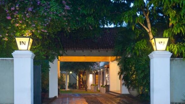 A hotel entrance with a covered walkway, white pillars, and a traditional roof. - Hotel Sunflower (Kataragama)