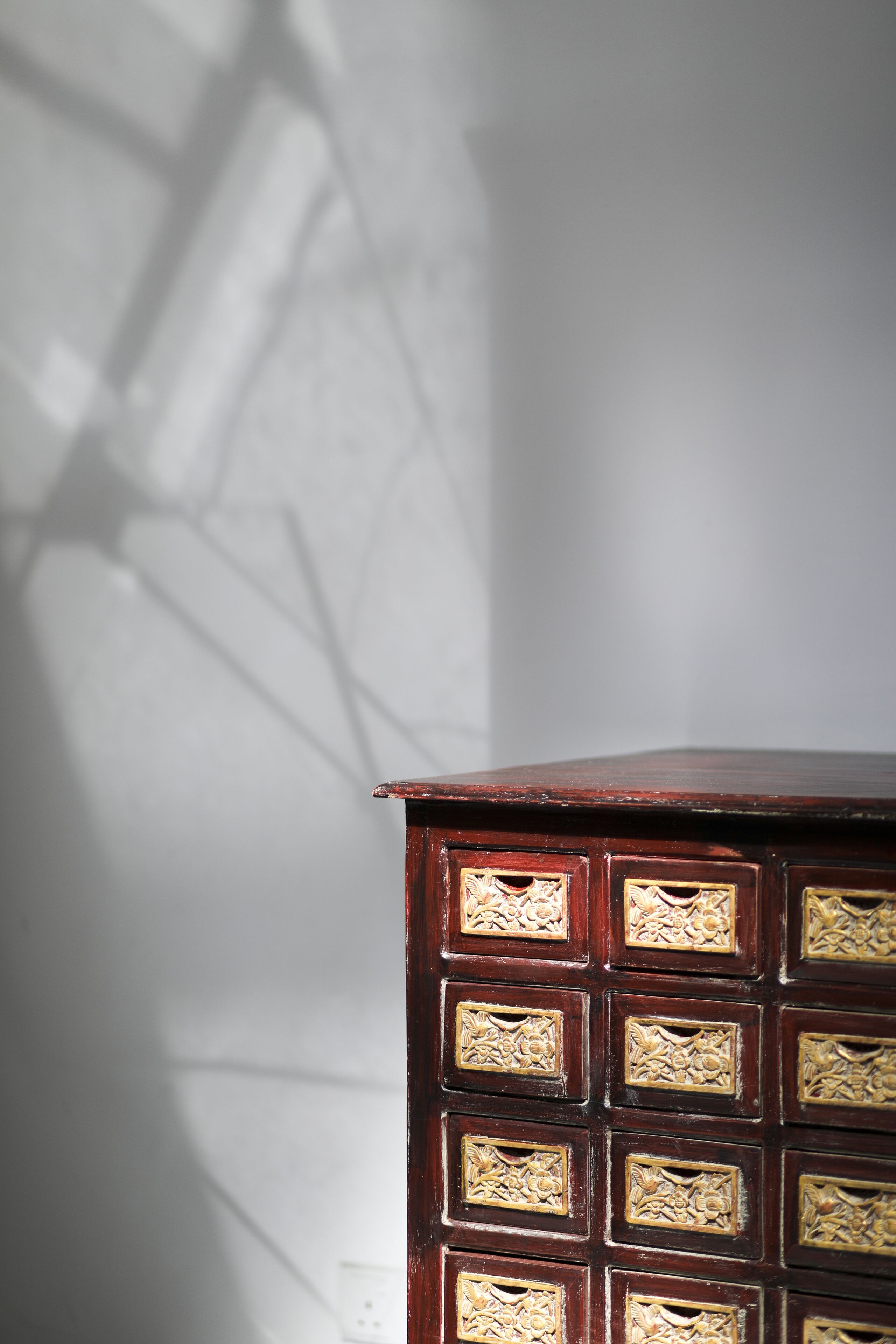 A wooden cabinet with multiple compartments against a plain wall.