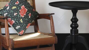 Una silla de madera con un cojín floral, una mesita redonda pequeña y un suelo a cuadros blancos y negros.