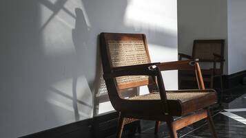 A wooden bench with a woven backrest against a wall, a tiled floor, and a shadow cast by a window.