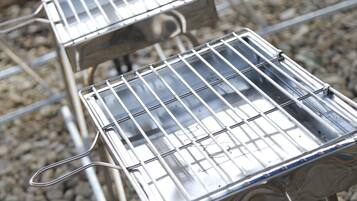 A row of metal barbecue grills on a gravel surface.