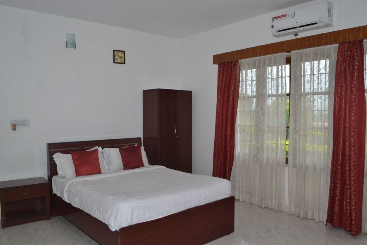 A bedroom with a bed, a wardrobe, and a window with curtains.