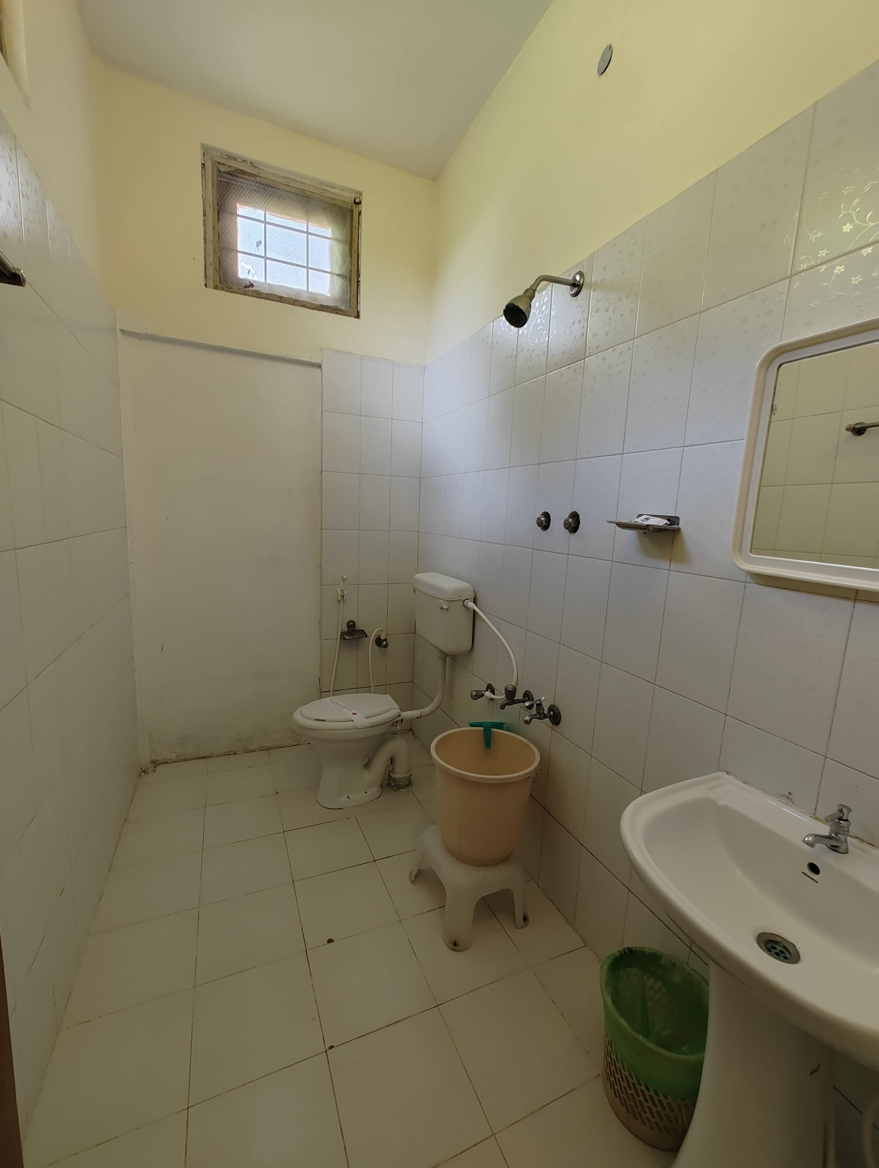 A small, basic bathroom with a toilet, a sink, and a window.