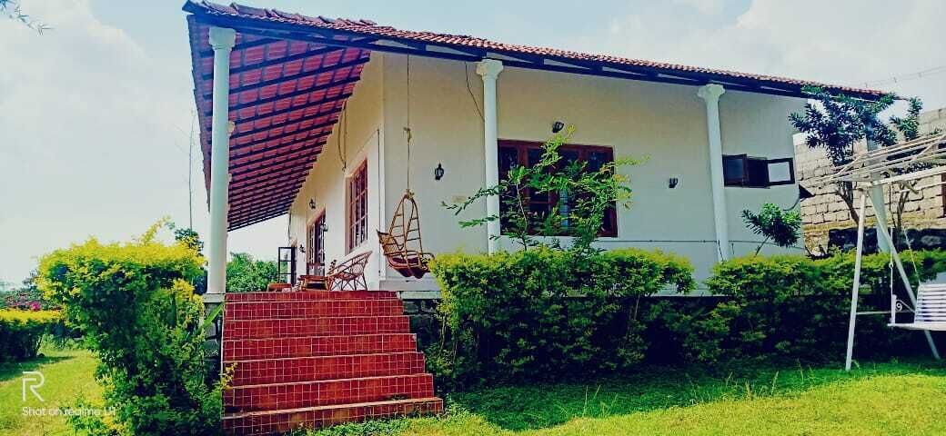 Una casa con porche de tejas rojas, una escalera que lleva a la entrada y una silla colgante.