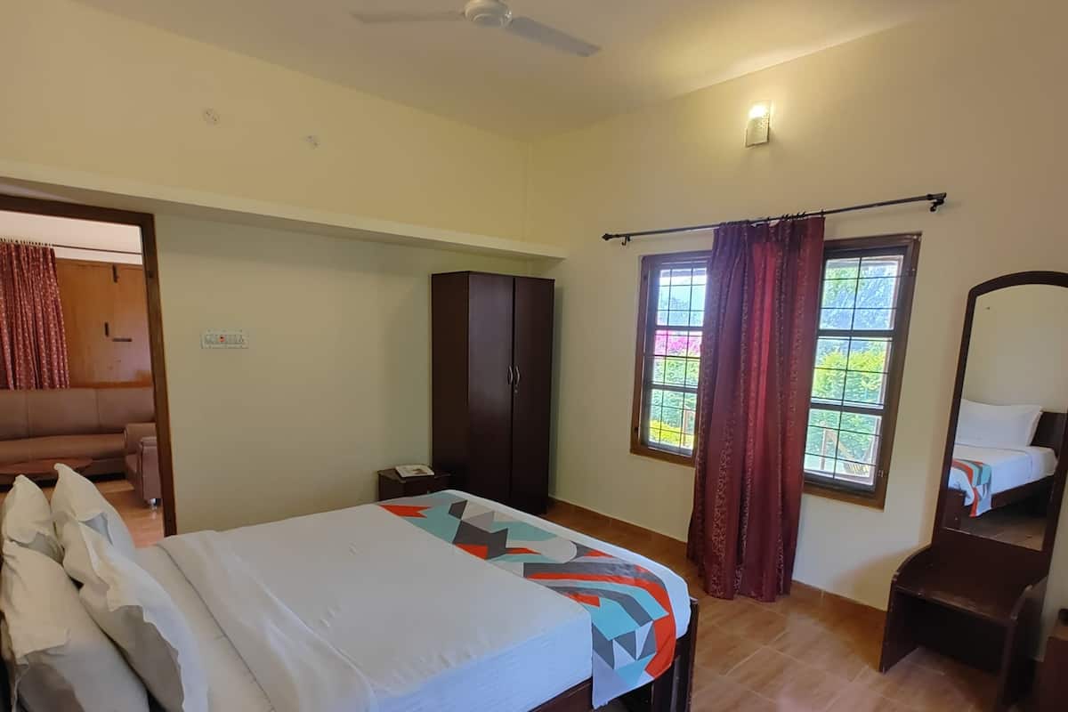 A bedroom with a bed, a wardrobe, a desk, and a window with curtains.