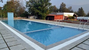 Ein rechteckiger Swimmingpool mit Fliesenrand, umgeben von einer Steindeck.