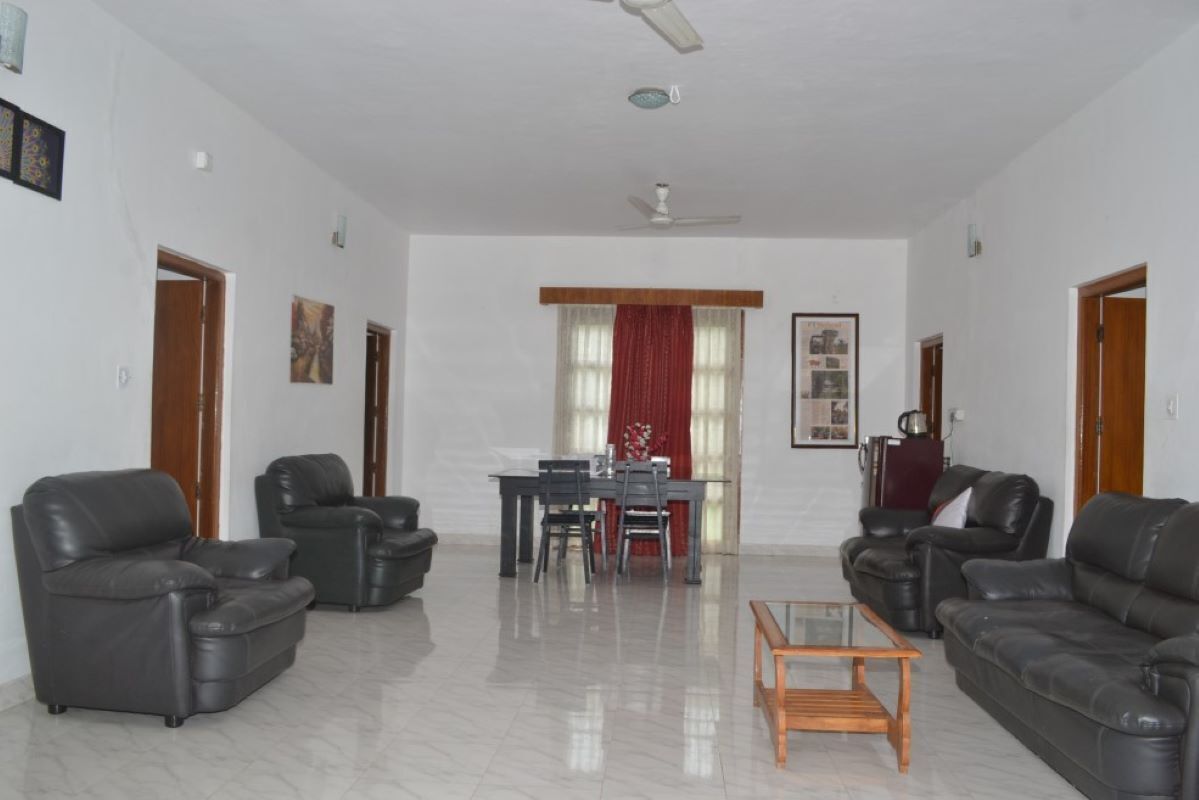 A spacious living room with a dining area, featuring a sofa set, a coffee table, and a dining table with chairs.