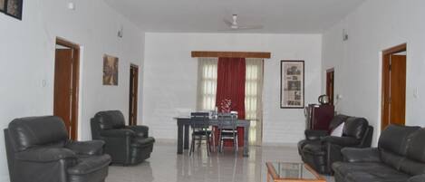 A spacious living room with a dining area, featuring a sofa set, a coffee table, and a dining table with chairs.
