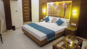 Un dormitorio ordenado con una cama grande, mesitas de noche y una mesa de centro de vidrio.