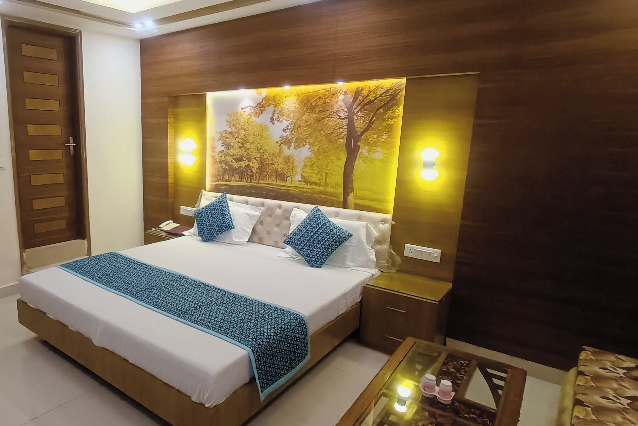 Une chambre à coucher bien rangée, avec un grand lit, une table de chevet, une commode et un téléviseur fixé au mur.