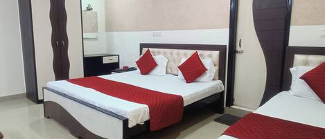 A hotel room with two beds, a wardrobe, a bedside table, and a mirror.