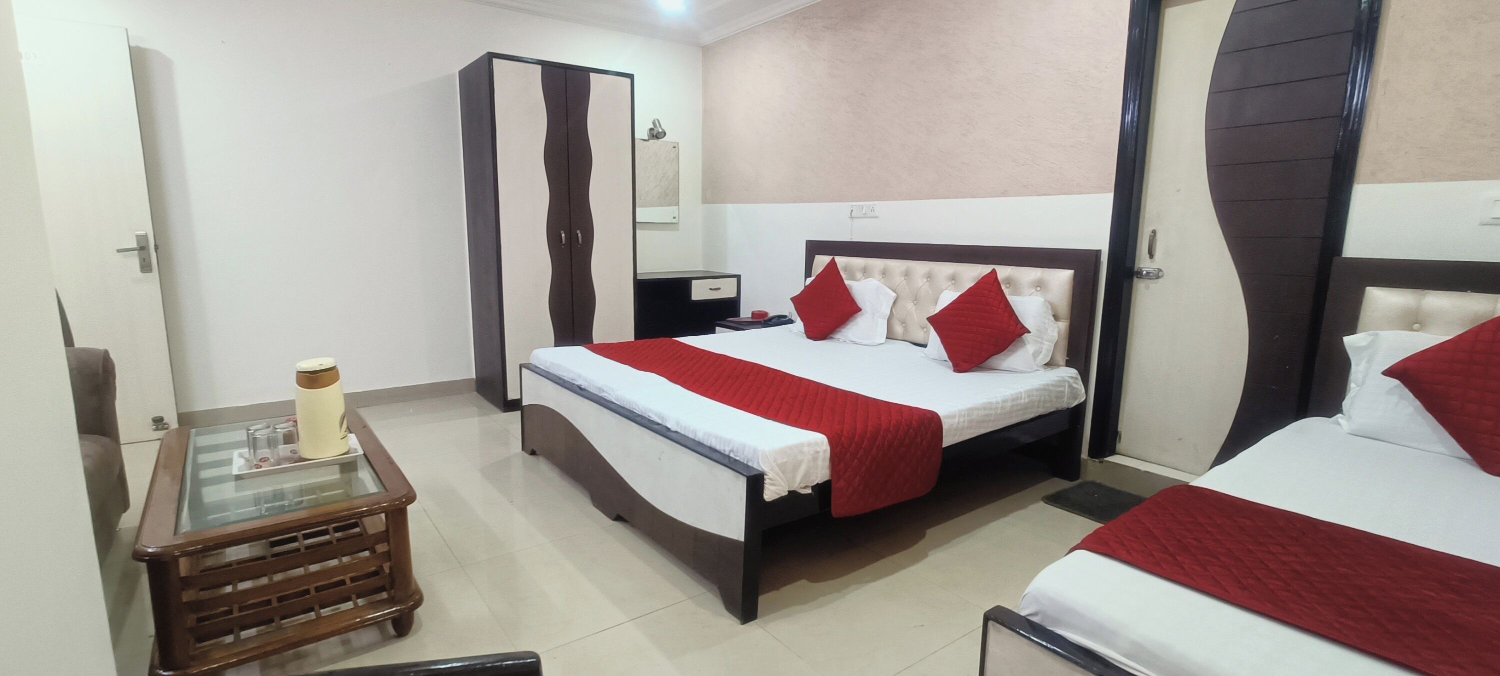 A hotel room with a bed, a wardrobe, a bedside table, and a mirror.