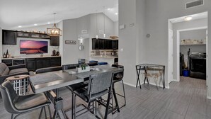 Una cucina moderna con mobili scuri, una grande isola centrale e luci a sospensione.
