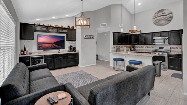 Una cucina moderna con mobili scuri, un'isola grande e una TV a schermo piatto.