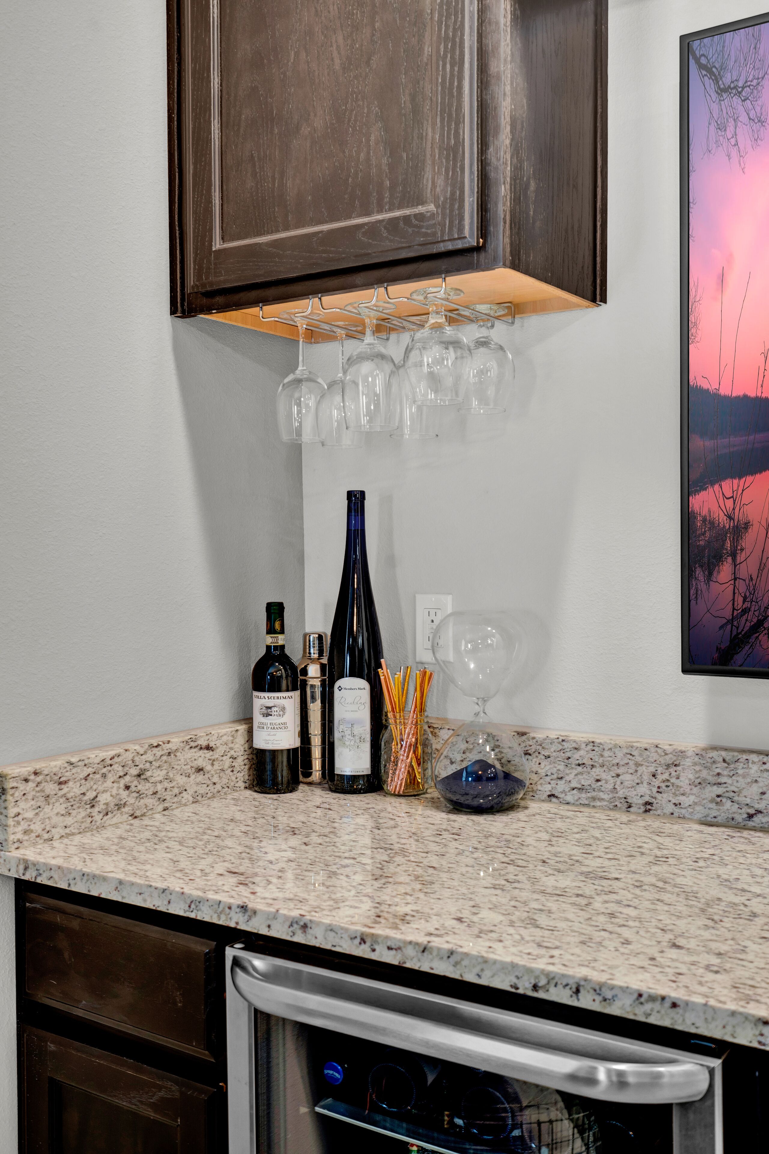 A kitchen counter with wine bottles, glasses, and a salt and pepper shaker.