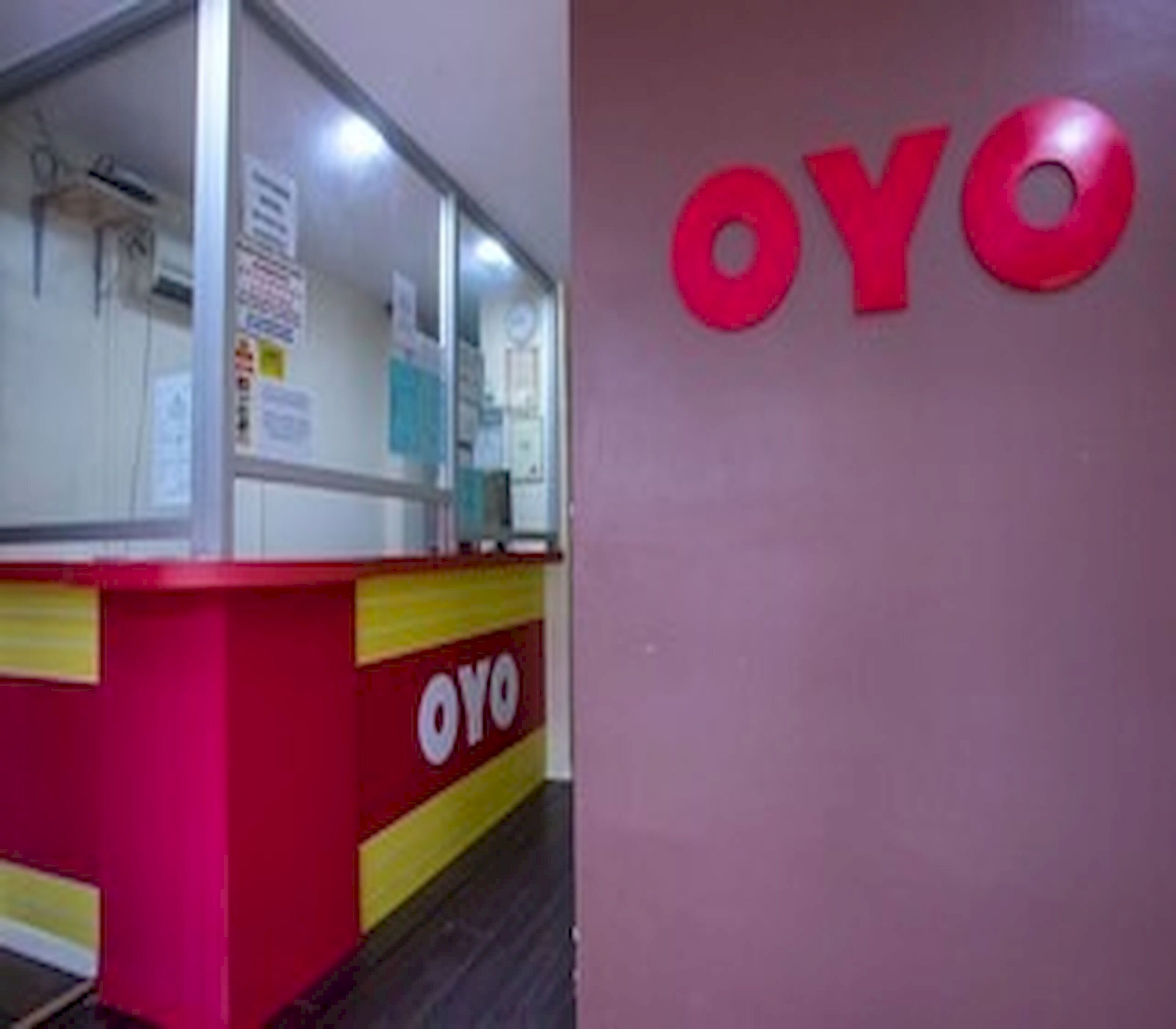A reception desk with a red and yellow color scheme and the logo 'OYO' on the wall.