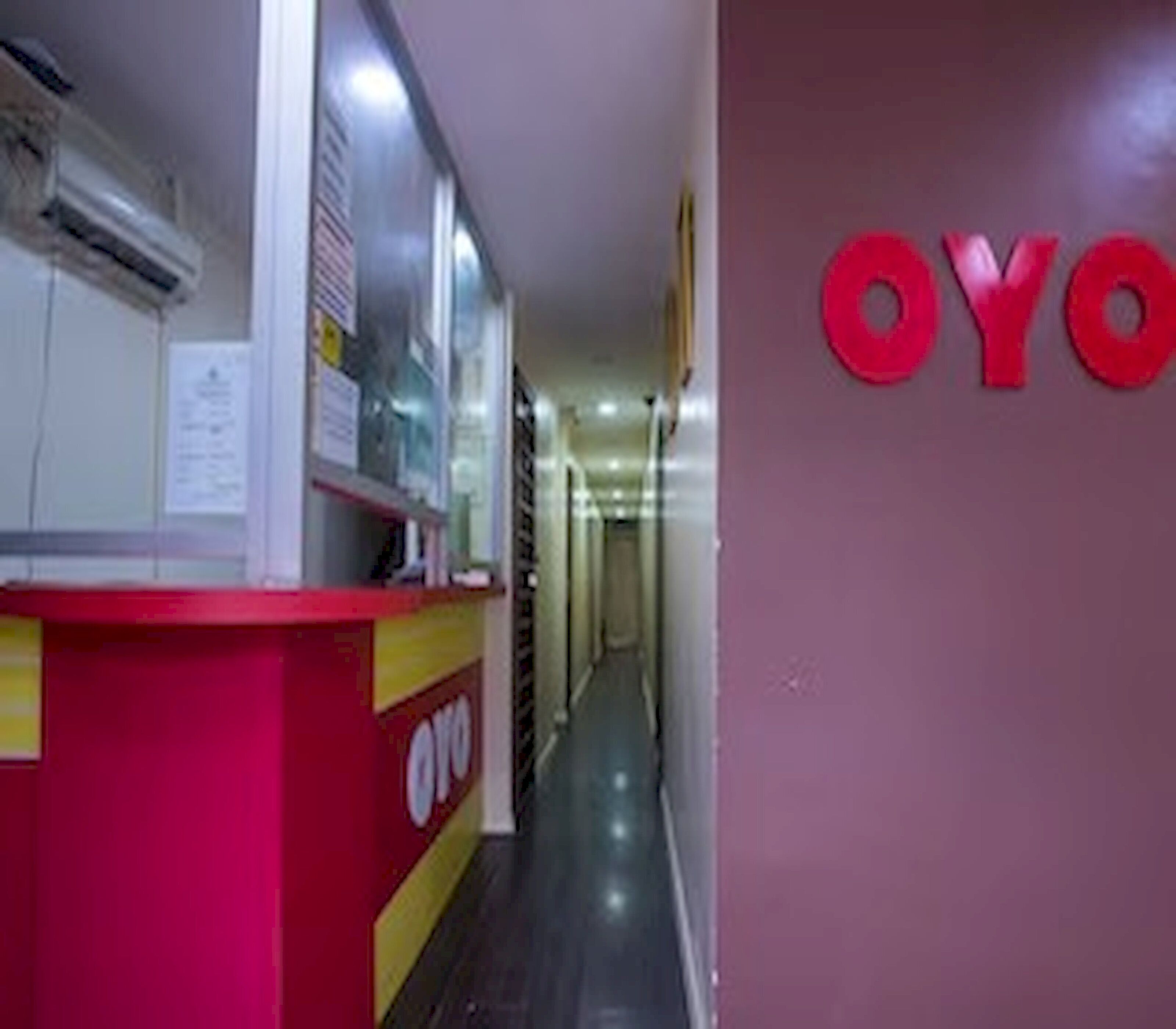 Um corredor com uma mesa de recepção e uma parede com as letras 'OYO' em vermelho.