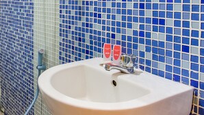 A bathroom with a white sink, blue mosaic tiles, and a shower with a handheld showerhead. - Hotel O Taj (seksyen 13) (Shah Alam)