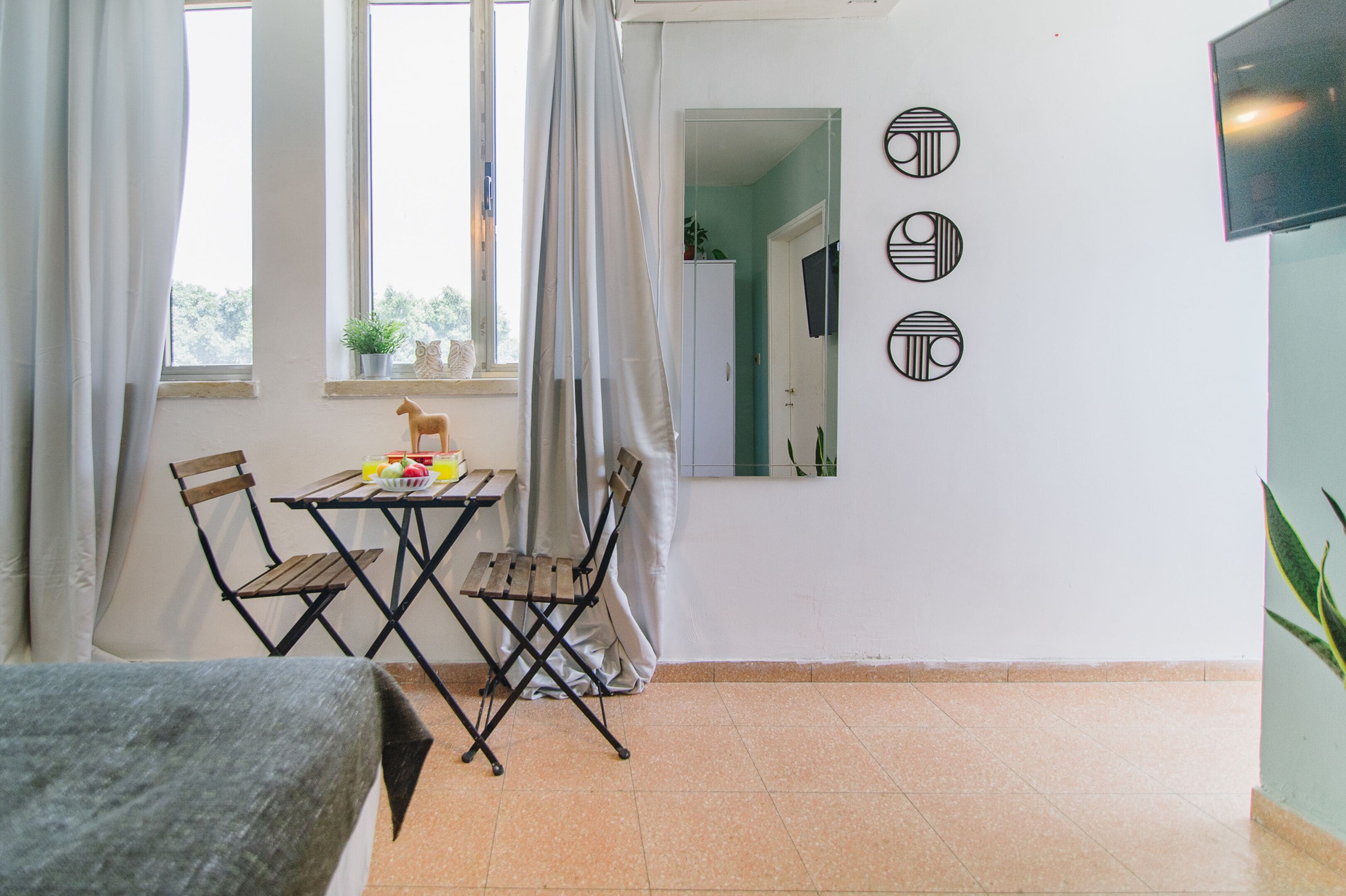 A room with a dining table and chairs, a small potted plant, and a mirror on the wall.