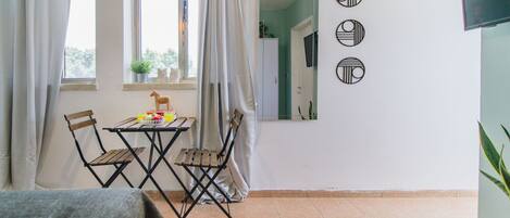 A room with a dining table and chairs, a small potted plant, and a mirror on the wall.