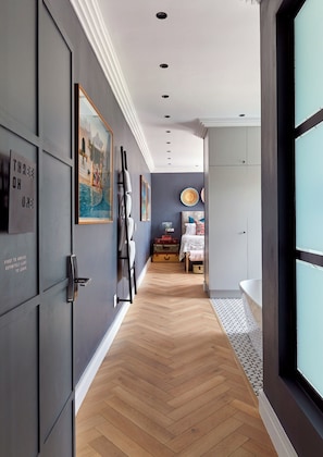 Un couloir doté d’un plancher en bois, de murs gris et d’œuvres d’art encadrées.