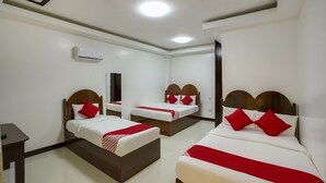 A hotel room with three beds, each with a wooden headboard and white bedding with red accents. There is a small table and a mirror on the wall. - OYO 459 Offshore Hotel (General Santos)