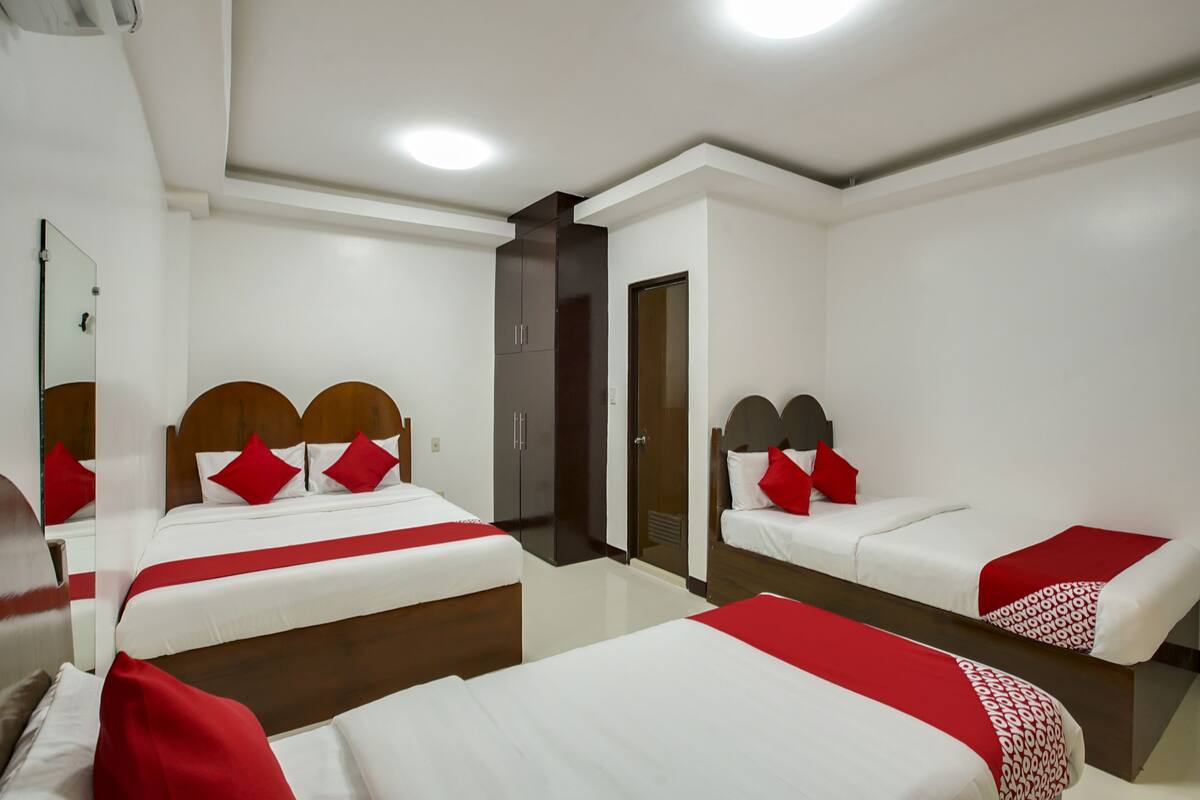 Quarto de hotel com duas camas, um guarda-roupa e um espelho.