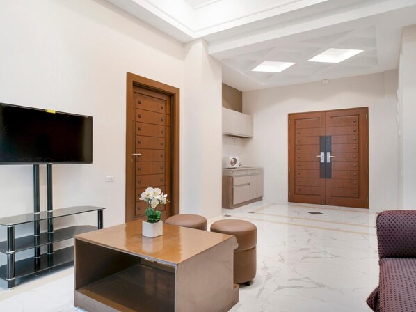 Een moderne woonkamer met een flatscreen televisie, een houten kast, een bank en een salontafel.