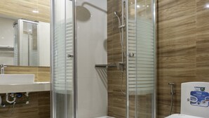Une salle de bain moderne avec une douche à parois de verre, un lavabo blanc et des toilettes.