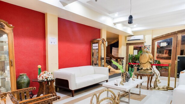 Un hall d’entrée spacieux, avec un canapé blanc, des chaises en bois, une table basse et des objets décoratifs.