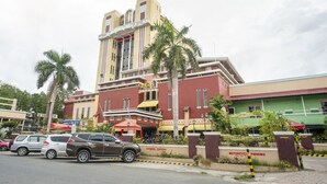 Un bâtiment à la façade rouge et beige, avec une enseigne indiquant « Stationnement en bataille », et un bâtiment vert situé à côté.