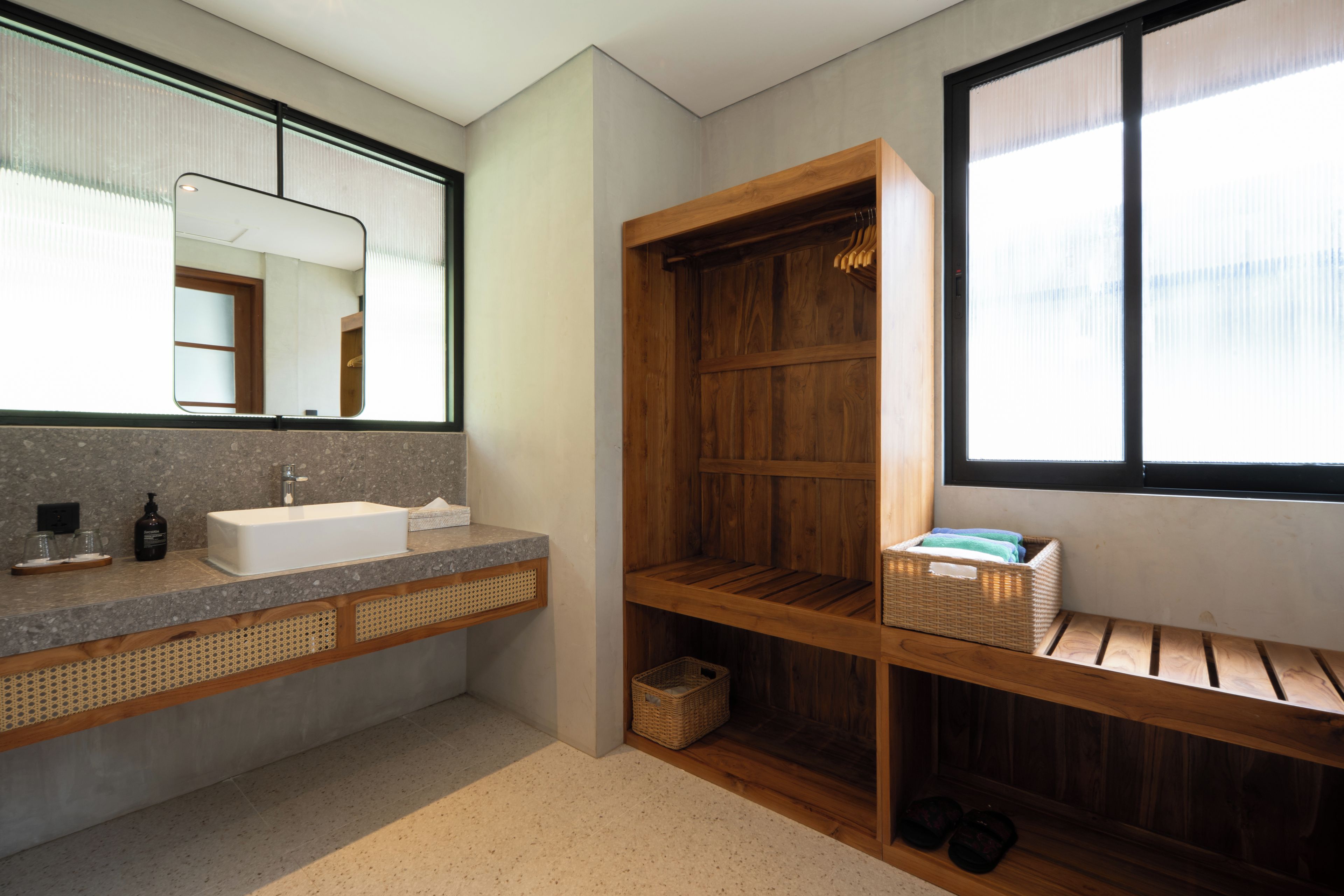 A bathroom with a large mirror, a sink, a wooden shelf, and a window.