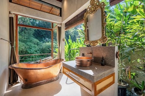 A bathroom with a freestanding bathtub, a sink, and a mirror. - Kadewa Retreat Ubud - Adults Only (Ubud)