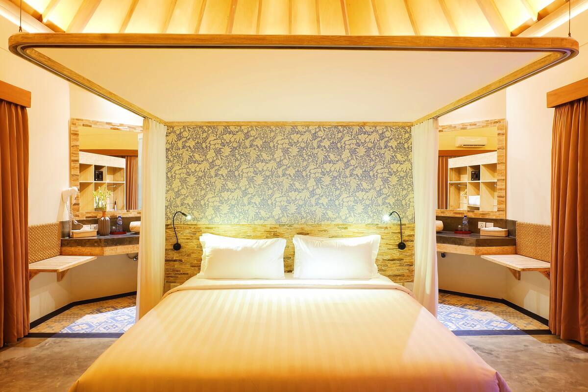 A hotel room with a large bed, two bedside tables, a mirror, and a patterned wall.