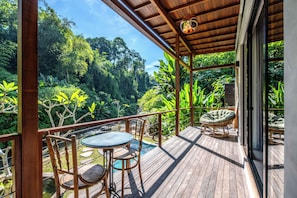A wooden deck with a table and chairs, overlooking a lush forest. - Kadewa Retreat Ubud - Adults Only (Ubud)