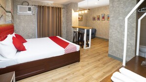 Una camera d'albergo moderna con un letto di legno, una scrivania e un’area pranzo.
