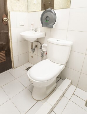 A bathroom with a toilet, a sink, and a paper towel dispenser. - OYO 471 Edilberto's B&B (Tagum)