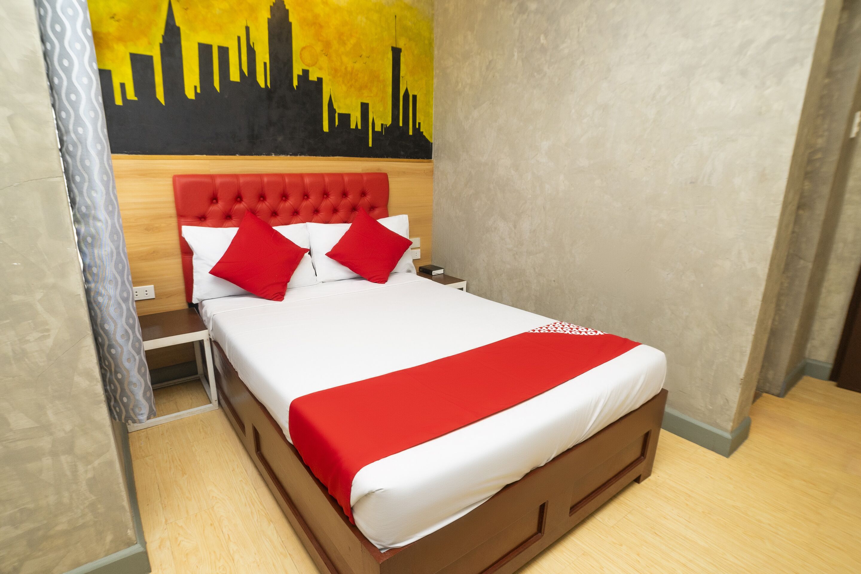 A neatly made bed with a red and white bedspread, two red pillows, and a wooden headboard.