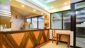 A reception area with a wooden reception desk, a clock, a small refrigerator, and a window with a view of the outside. - OYO 473 Ranchotel Drive-in (Biñan City)